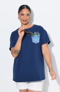 Námořnická modrá oversized tričko s denimovou kapsou zdobenou barevnou květinovou výšivkou. Krátké rukávy a kulatý výstřih.