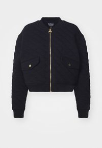 Jaqueta bomber preta com matelassê e fecho de zip dourado, dois bolsos frontais, punhos e bainha em canelado. Apresenta um colarinho redondo e um design cropped.