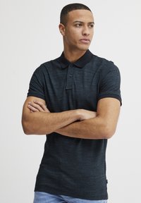 Polo noir avec un motif texturé, patte de boutonnage à trois boutons et col contrasté. Doté de manches courtes et d'une coupe slim.