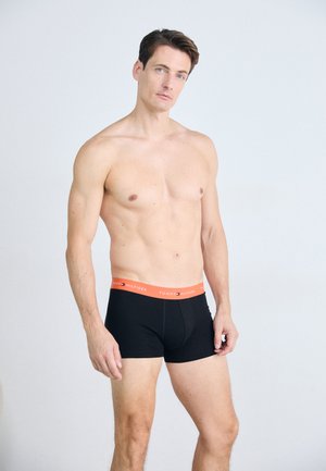 Schwarze Boxershorts mit einem orangefarbenen Bund, der das Logo "TOMMY HILFIGER" zeigt, aus einem glatten Stoff gefertigt, entworfen für eine figurbetonte Silhouette.