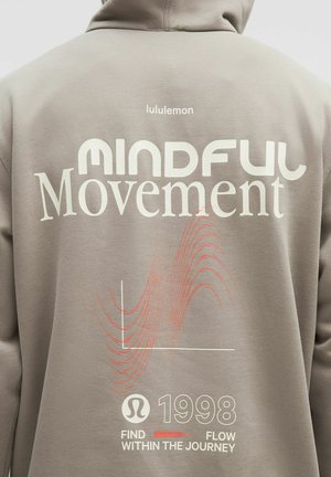 Hellgrauer Hoodie mit großen weißen und roten Text "MINDFUL Movement", wavy Liniengrafiken und "1998" am unteren Ende. Weicher Stoff.