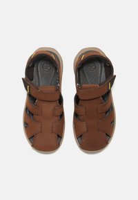 Ruske nahkasaappaat, joissa on nastat, avointen varpaiden muotoilu, kumipohjat ja sivuleikkaukset ilmanvaihtoa ja mukavuutta varten.