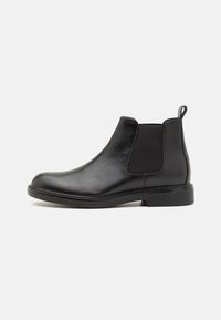 Bota Chelsea negra de cuero con paneles laterales elásticos, un acabado suave, punta redondeada y suela de goma baja y resistente.