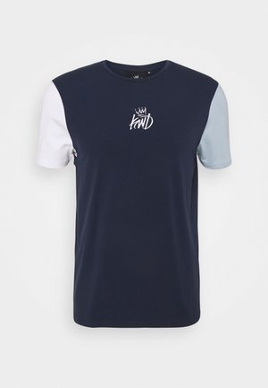 Maglietta blu navy con manica sinistra bianca e manica destra azzurra chiara, con una corona bianca e il logo "kwD" al centro del petto.