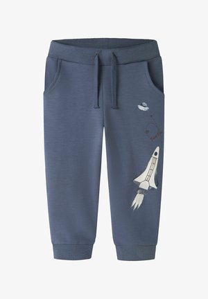 Pantaloni sport albaștri pentru copii, cu buzunare frontale, talie cu șnur și grafică tematică spațială cu rachetă și OZN pe piciorul drept.