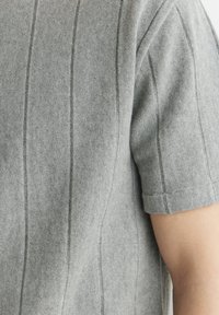 Szary sweter z krótkim rękawem o dzianinowej fakturze z pionowym prążkowaniem i kontrastowym wykończeniem, z okrągłym dekoltem i luźnym krojem.