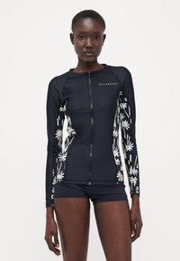 Marineblå langermet rash guard med hvit blomsterprint, glidelås foran og tett passform, kombinert med matchende marineblå shorts. Glatt stofftekstur.