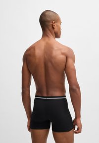 Black boxer briefs with a contrast elastic waistband. Soft, stretch fabric in a fitted design, showcasing a smooth texture and simple style.