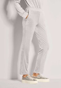 Lichtgrijze veloursbroek met taps toelopend ontwerp, voorzien van een gestructureerde afwerking, zijzakken en een elastische tailleband.