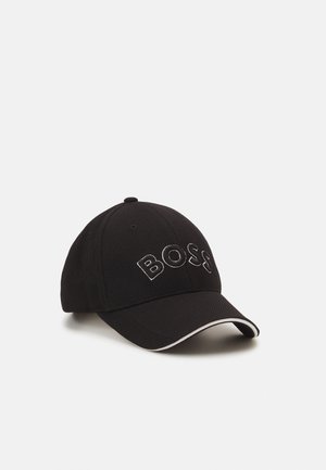 Casquette de baseball noire texturée avec une visière incurvée bordée de blanc et « BOSS » brodé en grandes lettres blanches à l’avant.