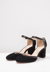 Černé semišové lodičky s kulatou špičkou, kotníkovým páskem a akcenty s krokodýlím vzorem. Mají pevný blokový podpatek.