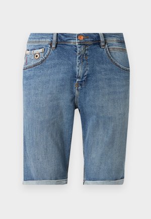 Mėlyni džinsiniai šortai iki kelių su priekinėmis kišenėmis, sagų užsegimu ir susuktais kraštais, parodyti ant vienodo fono.