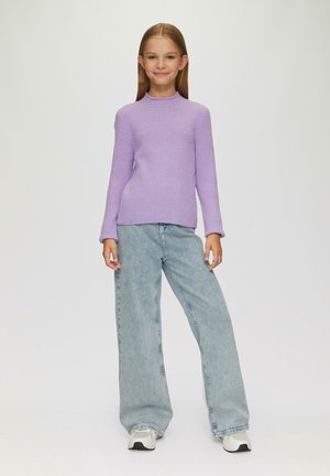 Lila rippstrukturierte Langarm-Bluse kombiniert mit hellblauen weiten Jeans und weißen Sneakers. Der Pullover hat einen hohen Kragen und einen taillierten Schnitt.