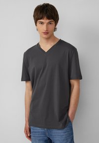 Węgorzysty szary t-shirt typu V-neck wykonany z miękkiej bawełny, z krótkimi rękawami i luźnym krojem. Subtelny detal z logo na piersi.