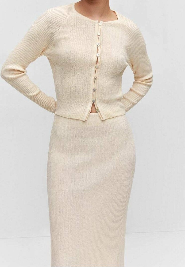 Cárdigan de punto en color beige claro con textura acanalada, mangas largas, escote cuadrado y cierre de botones, combinado con una falda a juego.