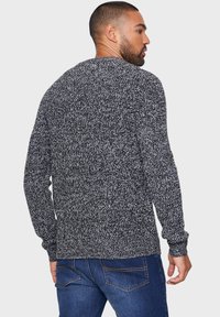 Maglione da uomo a collo rotondo in maglia nera e bianca strutturata. Presenta maniche lunghe e una vestibilità comoda. Dettagli visibili all'orlo e ai polsini.