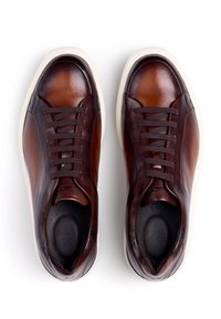 Braune Leder-Sneaker mit glatter Oberfläche, runder Spitze, kontrastierender weißer Gummisohle und sechs dunkelbraunen Schnürsenkeln. Markenlogo eingeprägt im Inneren.