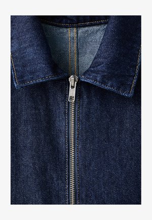 Teksas jakna tamnoplave boje, sa srebrnim patentnim zatvaračem, špicastim ovratnikom i vidljivim detaljima šavova duž spojnih linija.