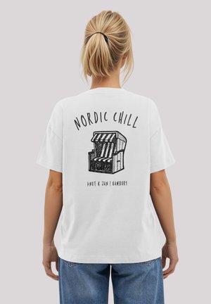 White oversized t-shirt featuring a graphic on the back with the text "NORDIC CHILL" and an illustration of a beach-style chair.