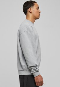 Maglione grigio realizzato in misto cotone, con collo rotondo, polsini e fondo a costine, maniche raglan e vestibilità rilassata.