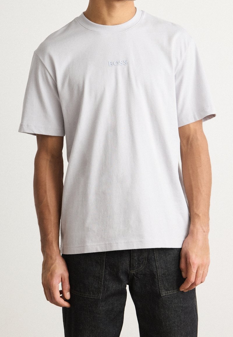 T-shirt à manches courtes gris clair en coton, arborant un logo en relief "BOSS" discret sur la poitrine et une coupe décontractée.