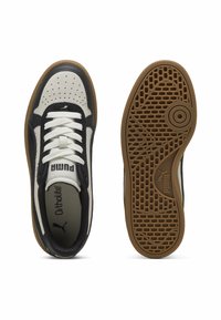 Puma tenisice u crnoj i krem boji s kožnim i zamščenim materijalima, bijelim vezicama, perforiranim prednjim dijelom i gumena potplata s geometrijskim uzorkom.