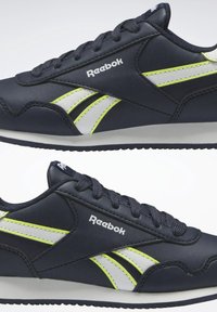 Marinblå lädersneakers med vita och neon-gula detaljer, snörning, vadderad krage och texturerad gummisula. Reebok-logotyp visas.