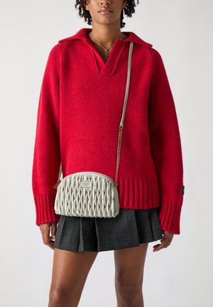 Maglione rosso a maglia con scollatura a V e orlo a coste, abbinato a una borsa a tracolla trapuntata grigia chiara con una catena e dettagli del logo.