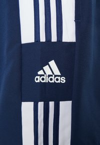 Námořnické sportovní tričko s bílými pruhy, s logem Adidas v bílé barvě. Hladká textura s prodyšným materiálem.