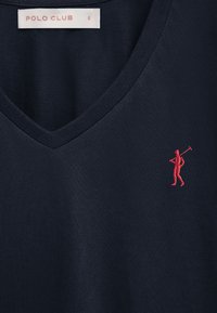 Navyblauw V-hals shirt met een rood geborduurd golferlogo op de rechterborst en een wit Polo Club maat klein label aan de binnenkant van de kraag.
