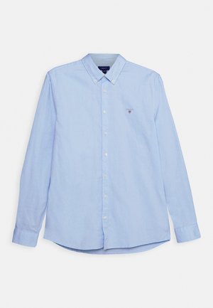 Chemise bleu clair à manches longues avec col boutonné et petit logo brodé sur la poitrine gauche.