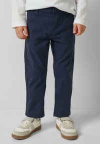 Námořnické modré bavlněné kalhoty s rovný střihem, s bočními kapsami a knoflíkovým zavíráním. Nosit s bílými teniskami a košilí s dlouhým rukávem.