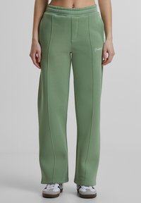 Groene katoen sweatpants met een brede pasvorm, voorzien van een naaddetail aan de voorkant en een elastische tailleband. Witte logo gedrukt aan de zijkant.