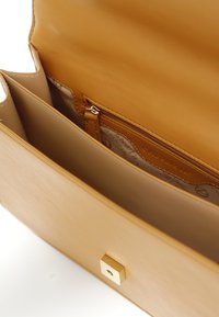 Tan læder håndtaske med en glat overflade, som har to rum og en lynlåslomme, pyntet med en guldfarvet firkantet hardware detalje.