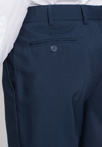 Pantaloni dress blu scuro con una texture liscia, taglio slim, una tasca posteriore con chiusura a bottone e passanti per cintura in vita.