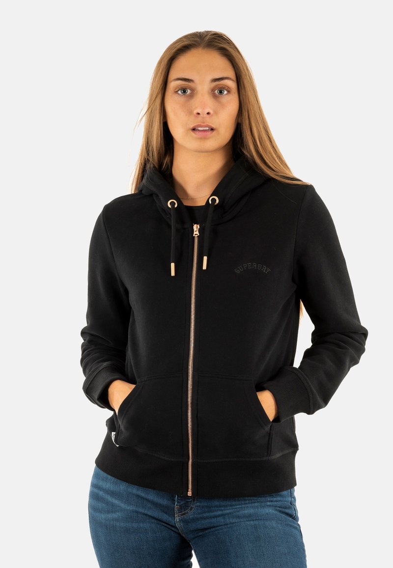 Felpa nera con zip realizzata in cotone con una consistenza morbida, dotata di cappuccio foderato, zip dorata e tasche anteriori.
