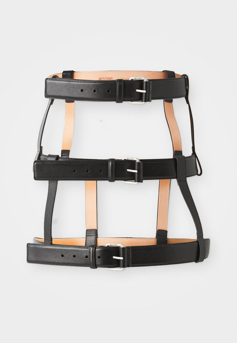 Arnés de cuero negro con acentos de cuero marrón. Presenta hebillas ajustables y varias correas horizontales y verticales. Textura suave.