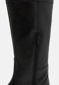 Bottes hautes noires en cuir avec motif floral embossé, fermeture éclair sur le côté et texture lisse. Conçues pour la durabilité et le style.
