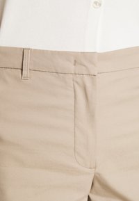 Beige Hosen mit glatter Textur, geradem Schnitt, Seitennähten und einem klassischen Bund mit verstecktem Knopf.