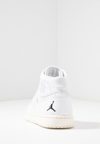 Sneaker alta bianca in pelle con design perforato, retro testurizzato, suola color crema e dettaglio logo nero sul tallone.
