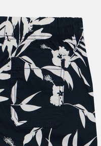 Marineblå shorts i stoff med hvit blomstermønster, elastisk livbånd og en baklomme med sømdetaljer.