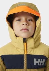 Chaqueta de invierno para niños en marrón y azul marino, con un acento naranja en la capucha, cremallera frontal y logotipo en el pecho.