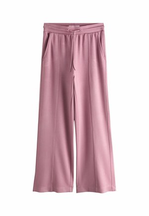 Person iført malva sweatpants med snørelukning i taljen og matchende top, der viser ringe på begge hænder.