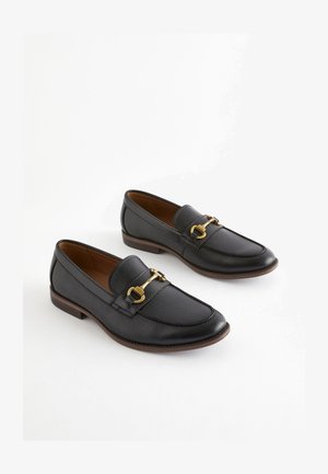 Melnas ādas loaferi ar apaļu purngalu, zelta aksesuāru akcentu un teksturētu virsmu. Zems papēdis un gluda iekšējā oderējuma.