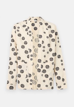 Krém hosszú ujjú blézer fekete körmintákkal és két első zsebbel, egyszínű világos háttér előtt bemutatva.