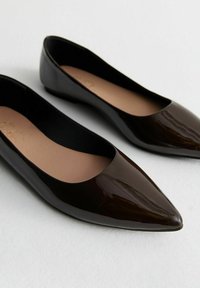 Glossy black ballet flats with a pointed toe and minimalistic design. Smooth exterior, with a beige insole and a small heel.