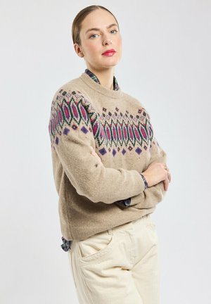Beige trui met kleurrijke geometrische patronen in paars en groen, ronde halslijn, textuur van wollen stof, gecombineerd met lichte broeken.