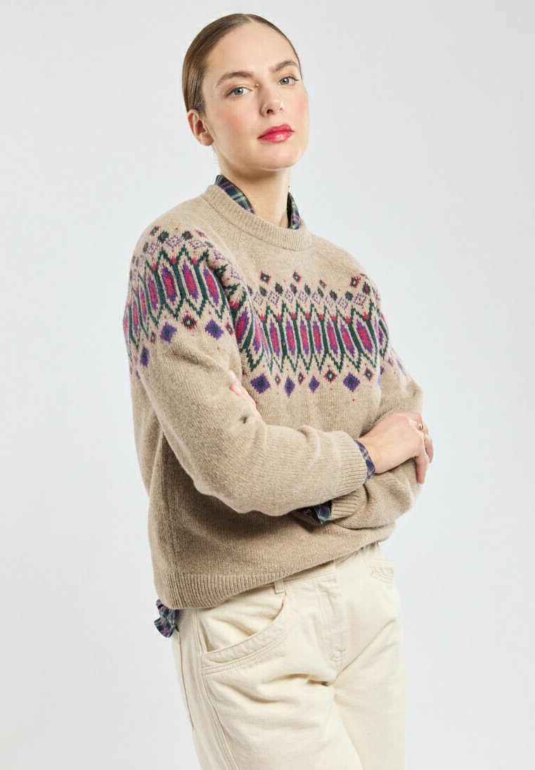 Beige trui met kleurrijke geometrische patronen in paars en groen, ronde halslijn, textuur van wollen stof, gecombineerd met lichte broeken.