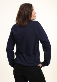 Sudadera azul marino de manga larga, con cuello redondo y textura suave y lisa. Presenta un corte relajado y detalles mínimos.