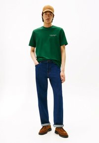 Grøn bomulds t-shirt med logo, blå denim jeans og brune suedesko. Klassisk pasform, foldede manchetter og lige ben-design.